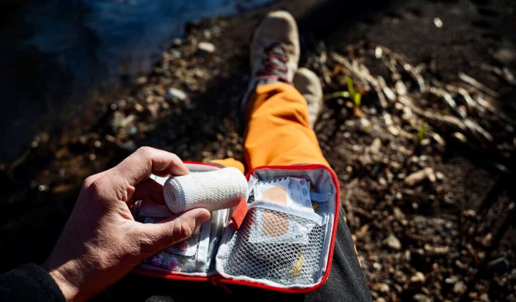 A traveler taking a break from hiking to use their first aid kit