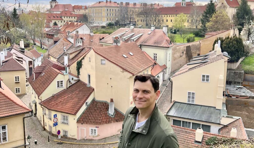 Nomadic Matt posing for a photo near old buildings in Prague, Czechia